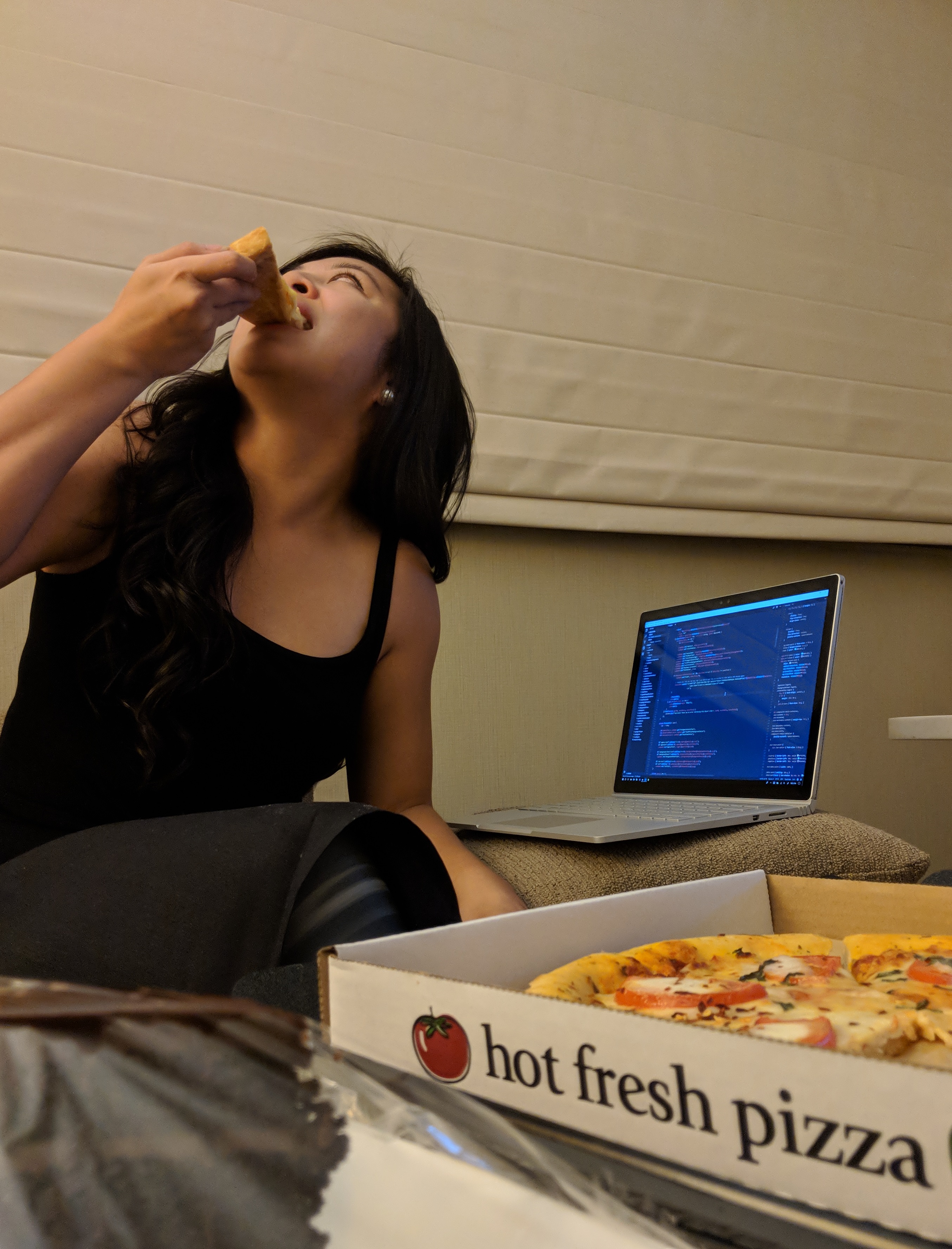Adrienne eating a pizza in her hotel room.