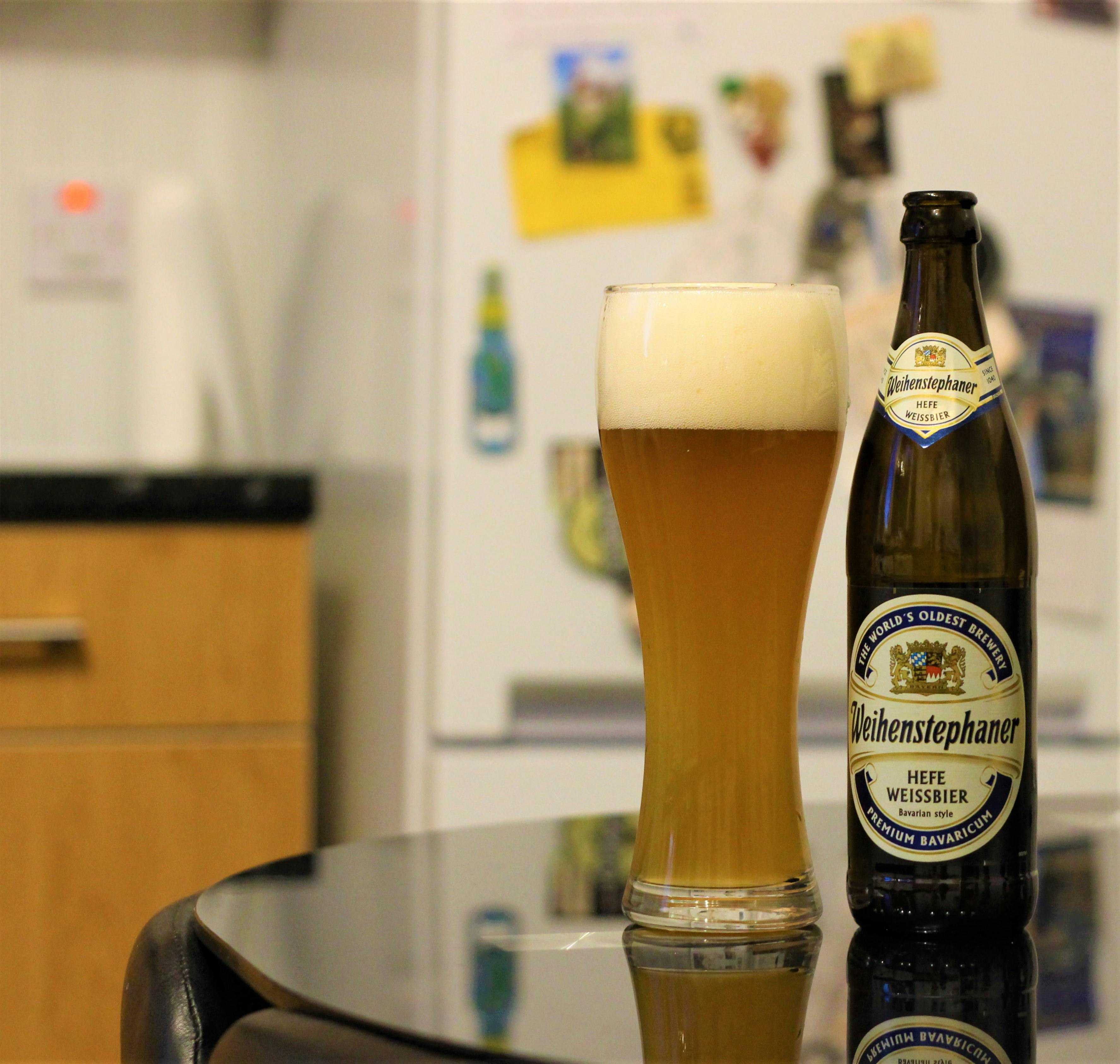 bottle of weihenstephaner sitting on a table next to a full glass of the beer