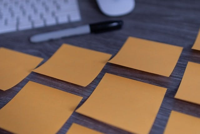 Group of blank sticky notes on a desk with a sharpie marker