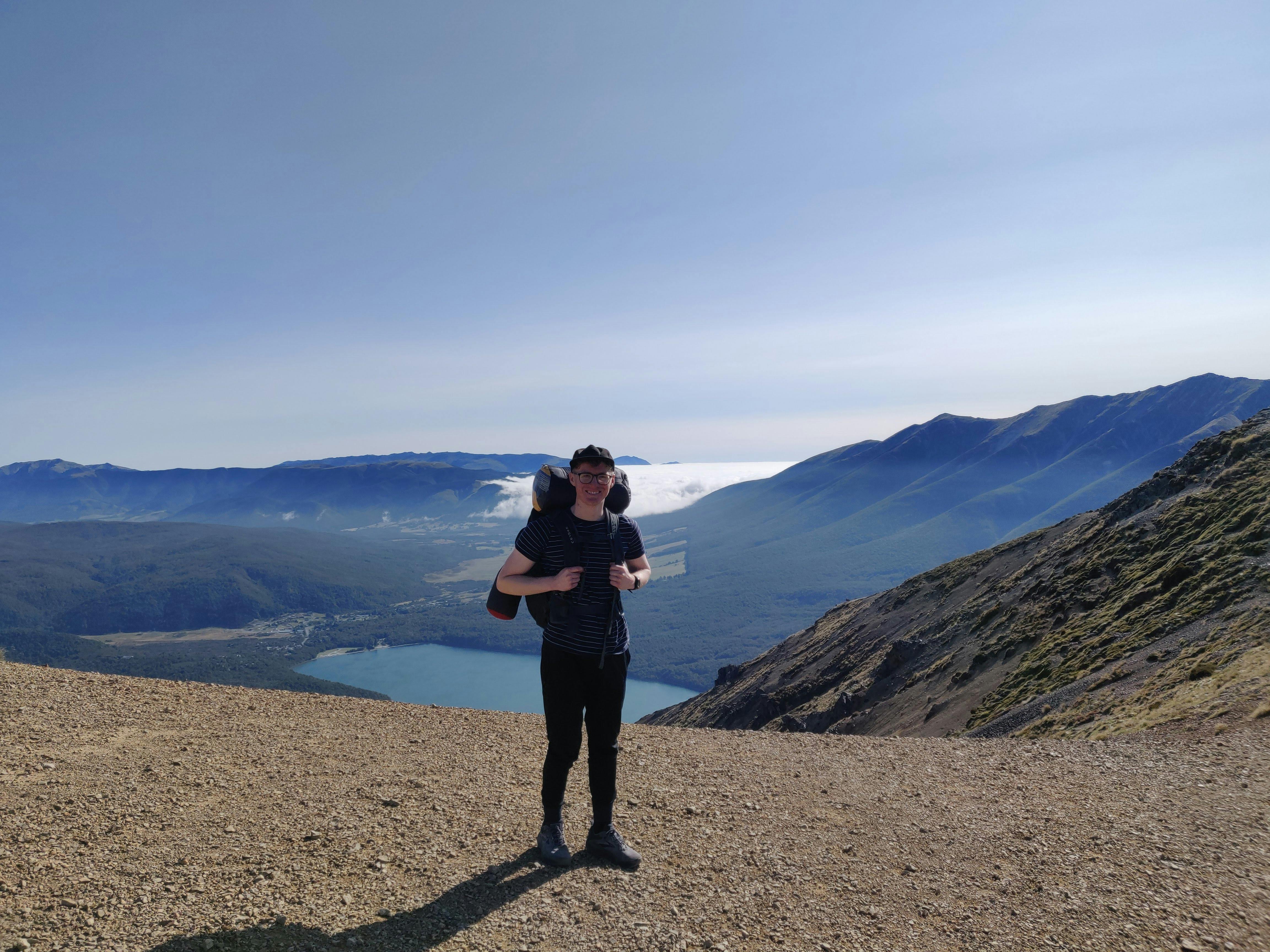 Me on top of a mountain with a landscape view of Nelson lakes behind
