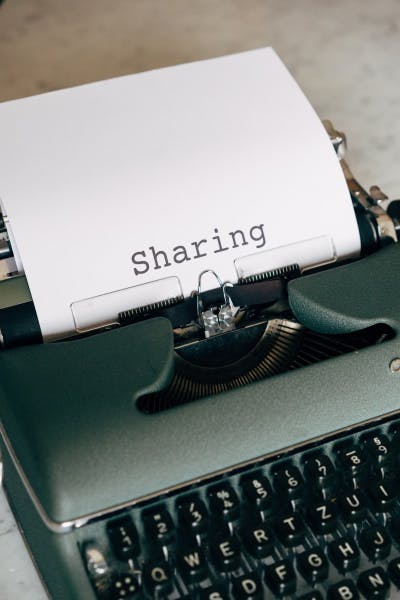 A typewriter with a sheet of paper that says sharing.