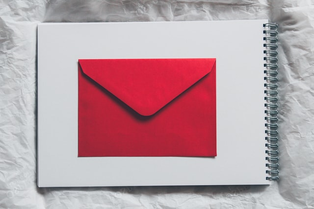 A red envelope sitting on top of a white sheet of paper.