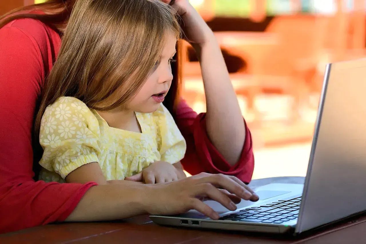 A man showing a little girl images on a laptop