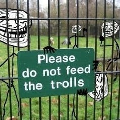 Please don't feed the trolls sign on a fence meme troll faces on stick figures behind the fence