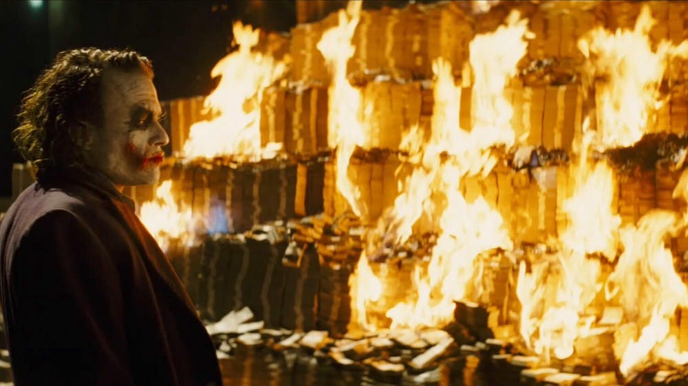 Joker staring at burnt pile of money
