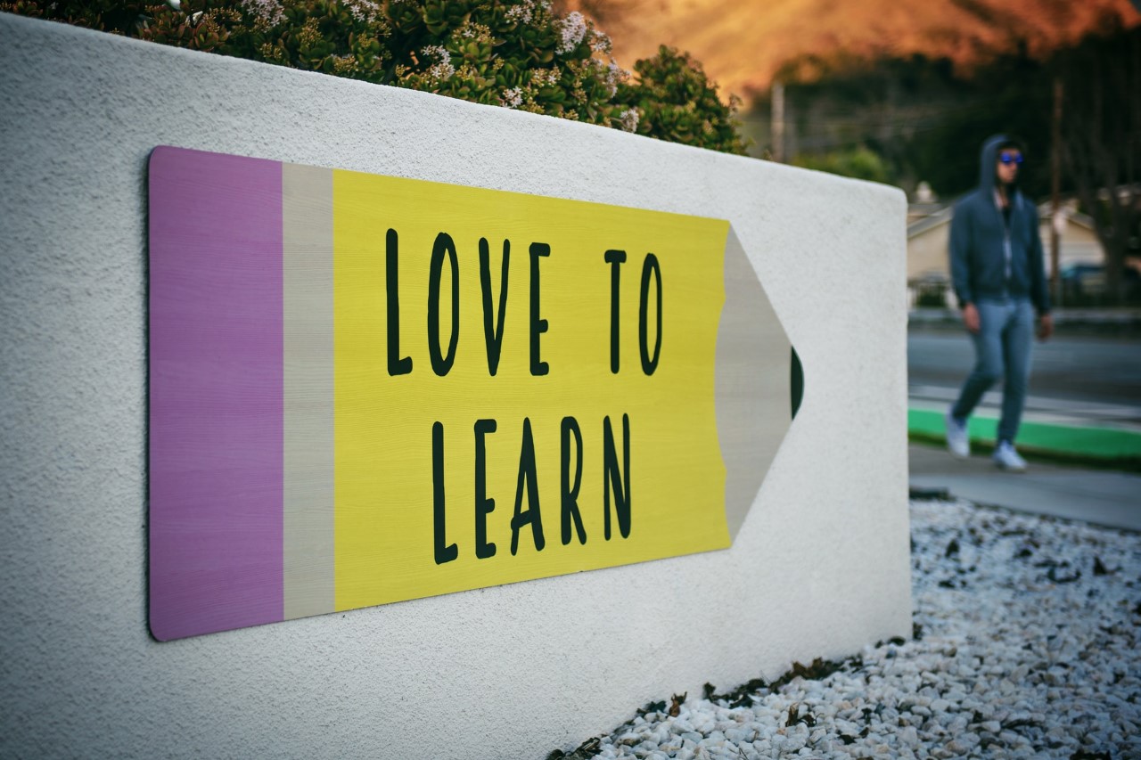 A man walking past a sign that says love to learn.