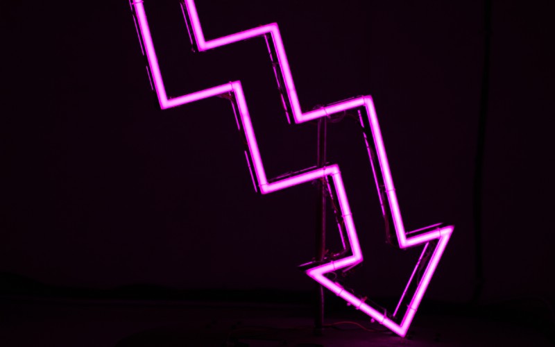A neon sign in the shape of a downward-facing arrow