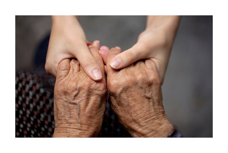 Holding hands, one pair from an elderly one pair from a young person