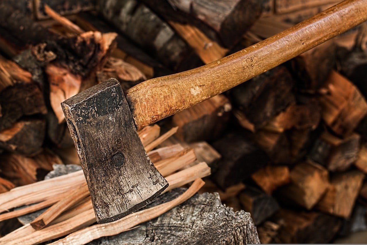 An image of an axe next to split wood