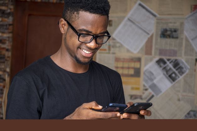 shallow-focus-young-african-male-with-glasses-usingphones-room.jpg