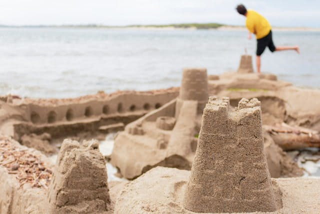 An expertly constructed sandcastle in front of a picturesque body of water.