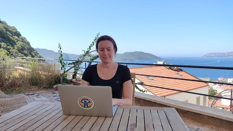 kobieta-pracuje-na-laptopie-w-tle-dachy-morze-i-wyspy