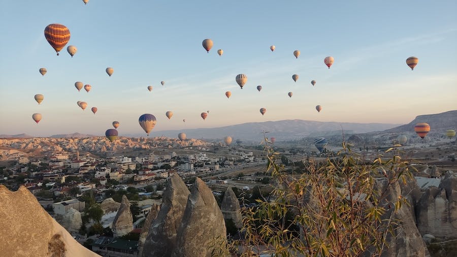 dziesiątki balonów unoszących się nad miastem Goreme i skalnymi stożkowatymi formacjami i 