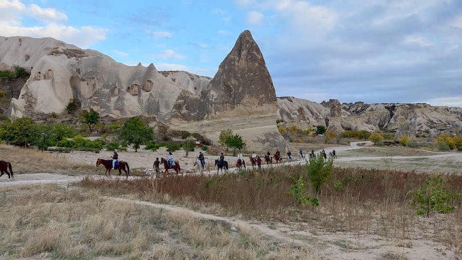 grupa osób na koniach, ciekawie uformowane, stożkowate skały