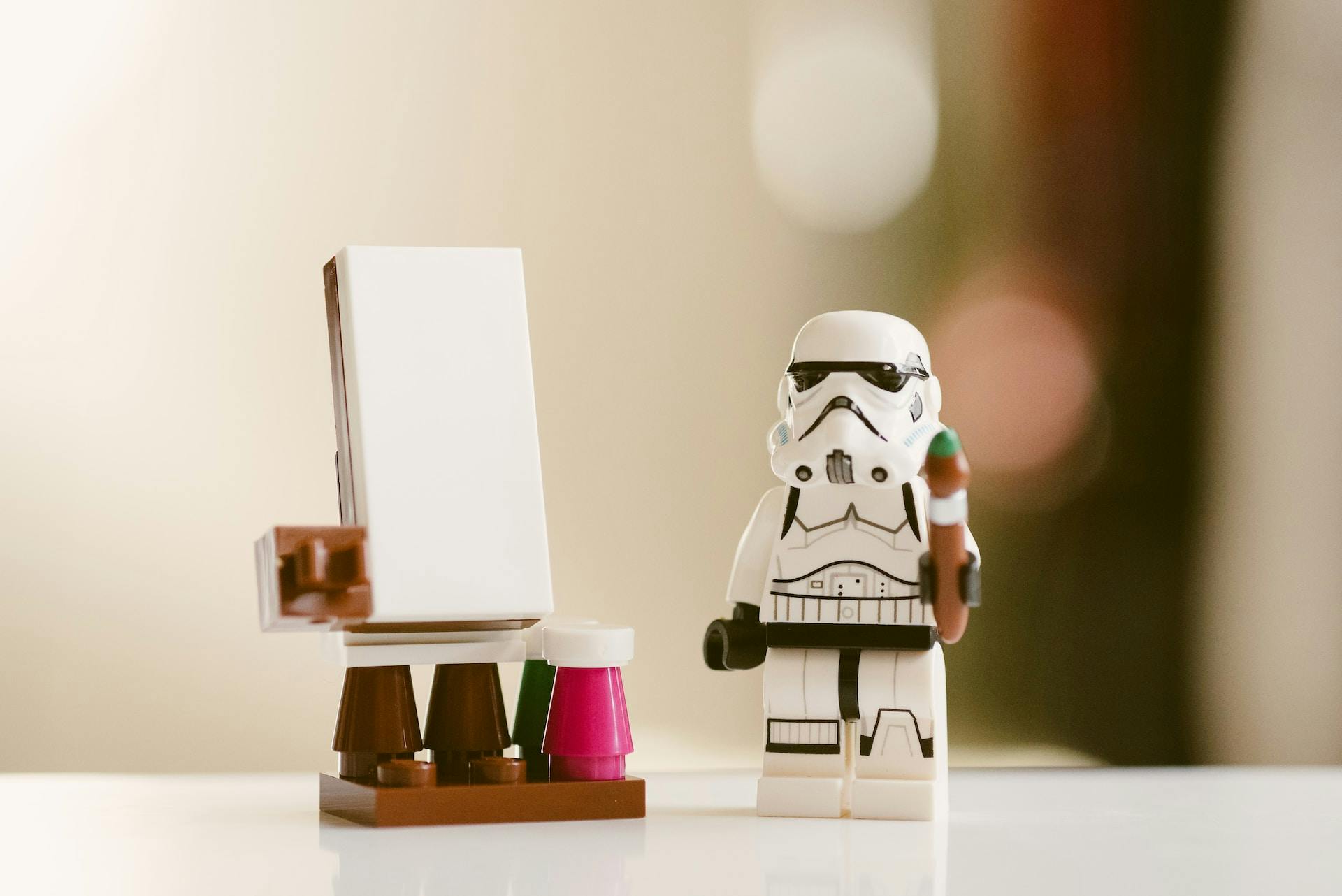 Lego storm trooper holding a paintbrush next to a blank canvas