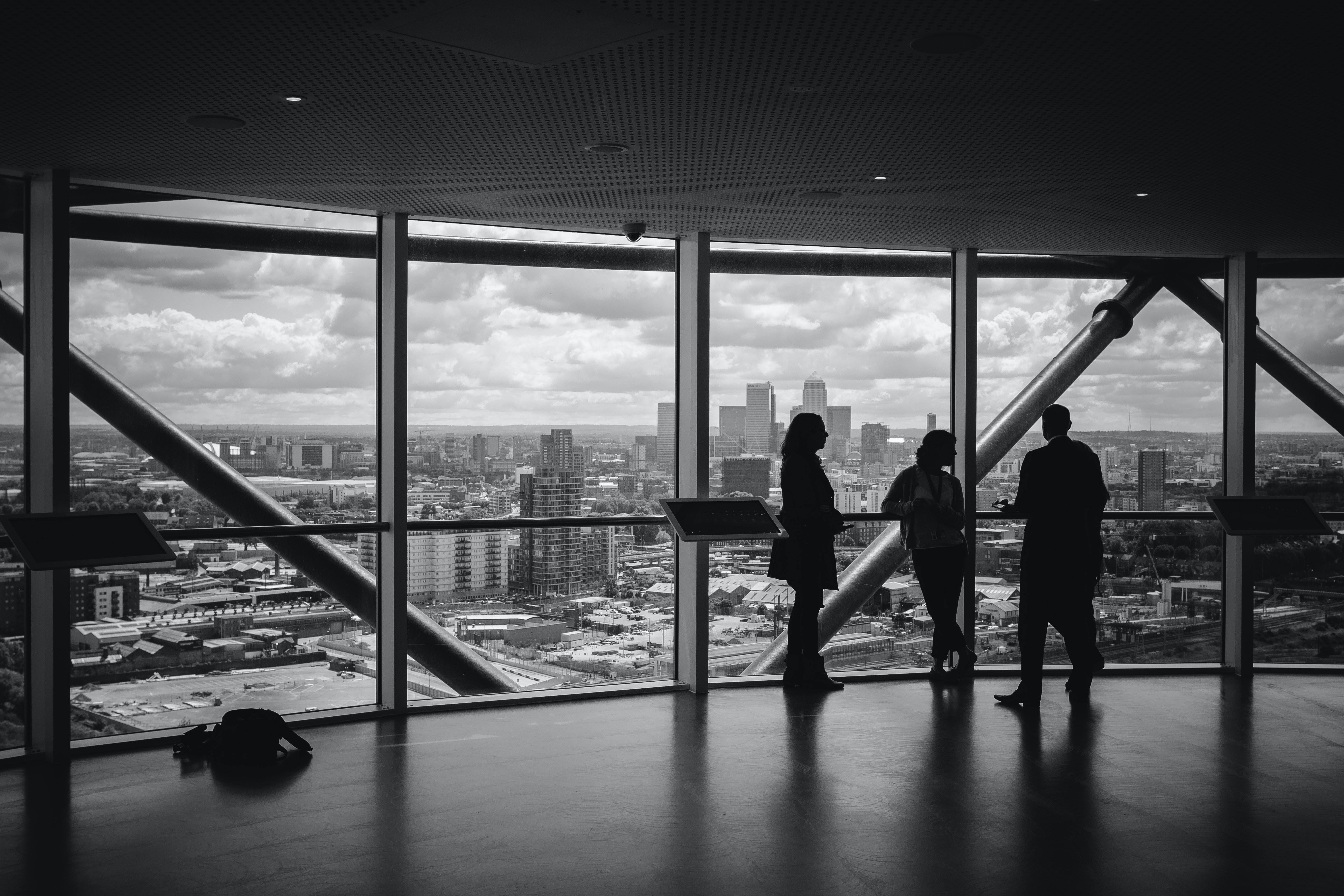 A picture of 3 people in a corporate meeting with a view of a city skyline captured and edited beautifully, shared by Charles Forerunner on Unsplash.