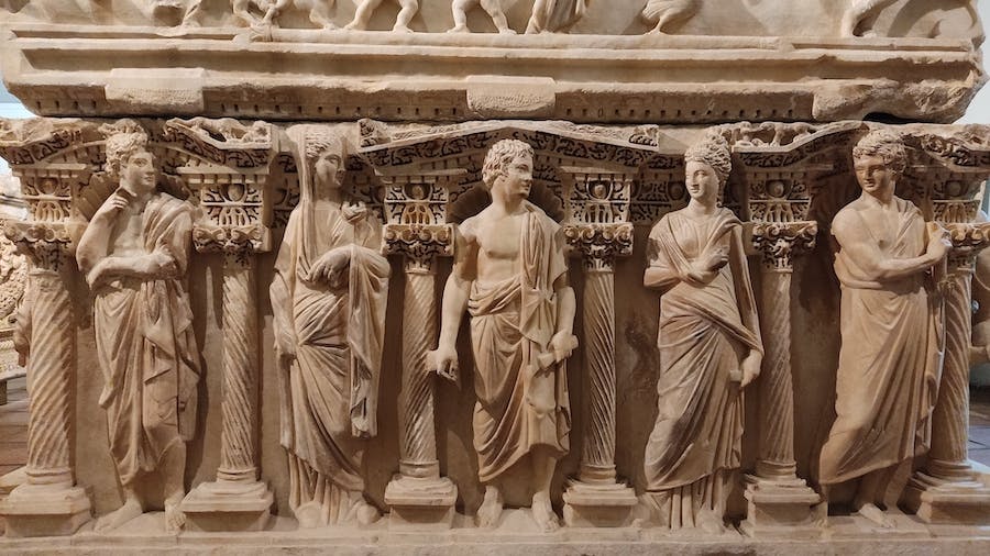 duży sarkofag z marmuru, ozdobiony rzeźbieniami kolumn i postaci w togach