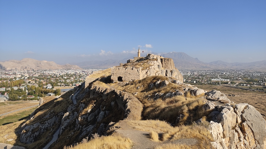 forteca z widocznym minaretem pooona na skalnym wzniesieniu, w tle miasto a dalej gry