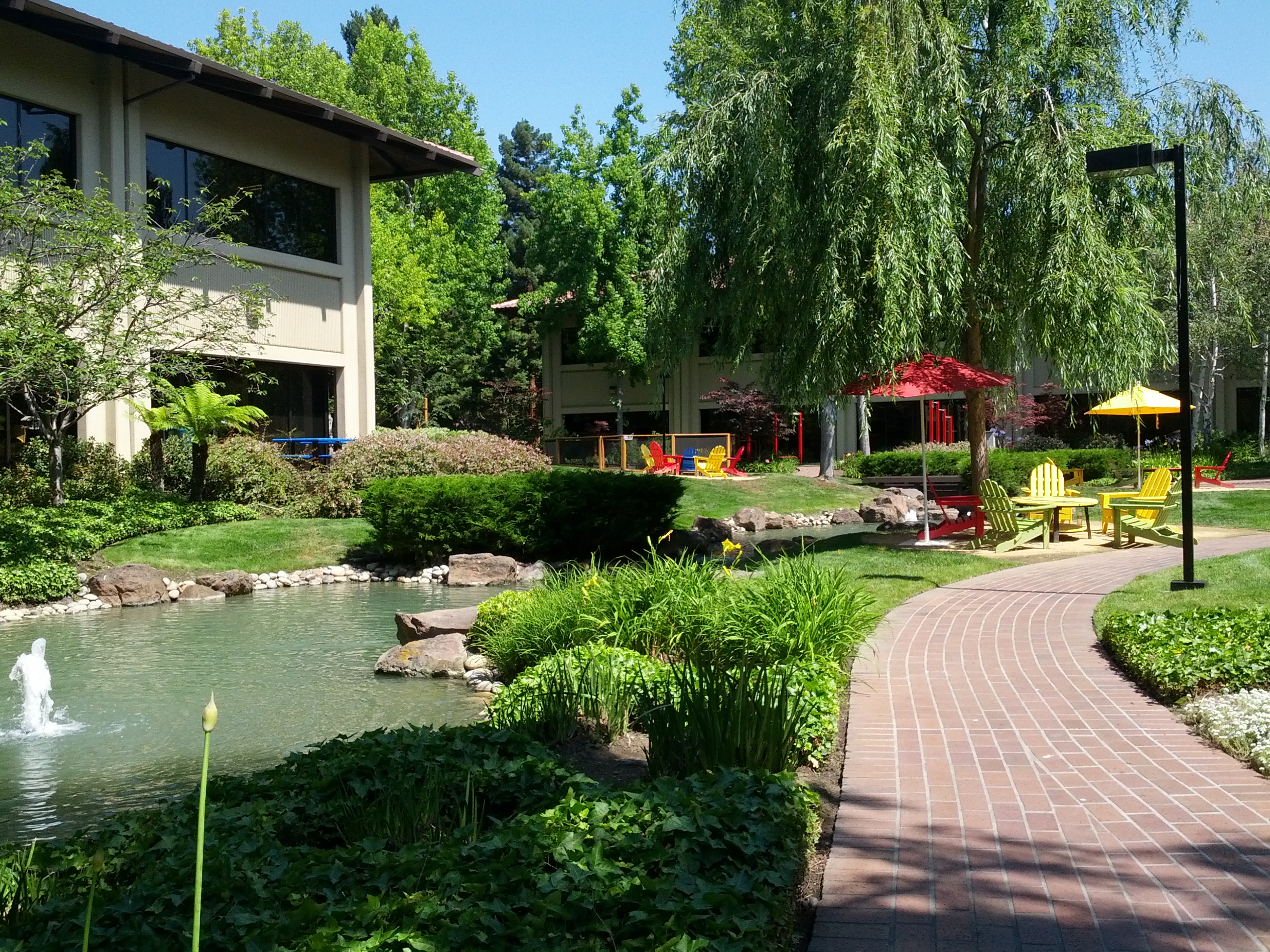 photograph of grounds at Google headquarters, with lawn chairs, picnic tables, and a pond