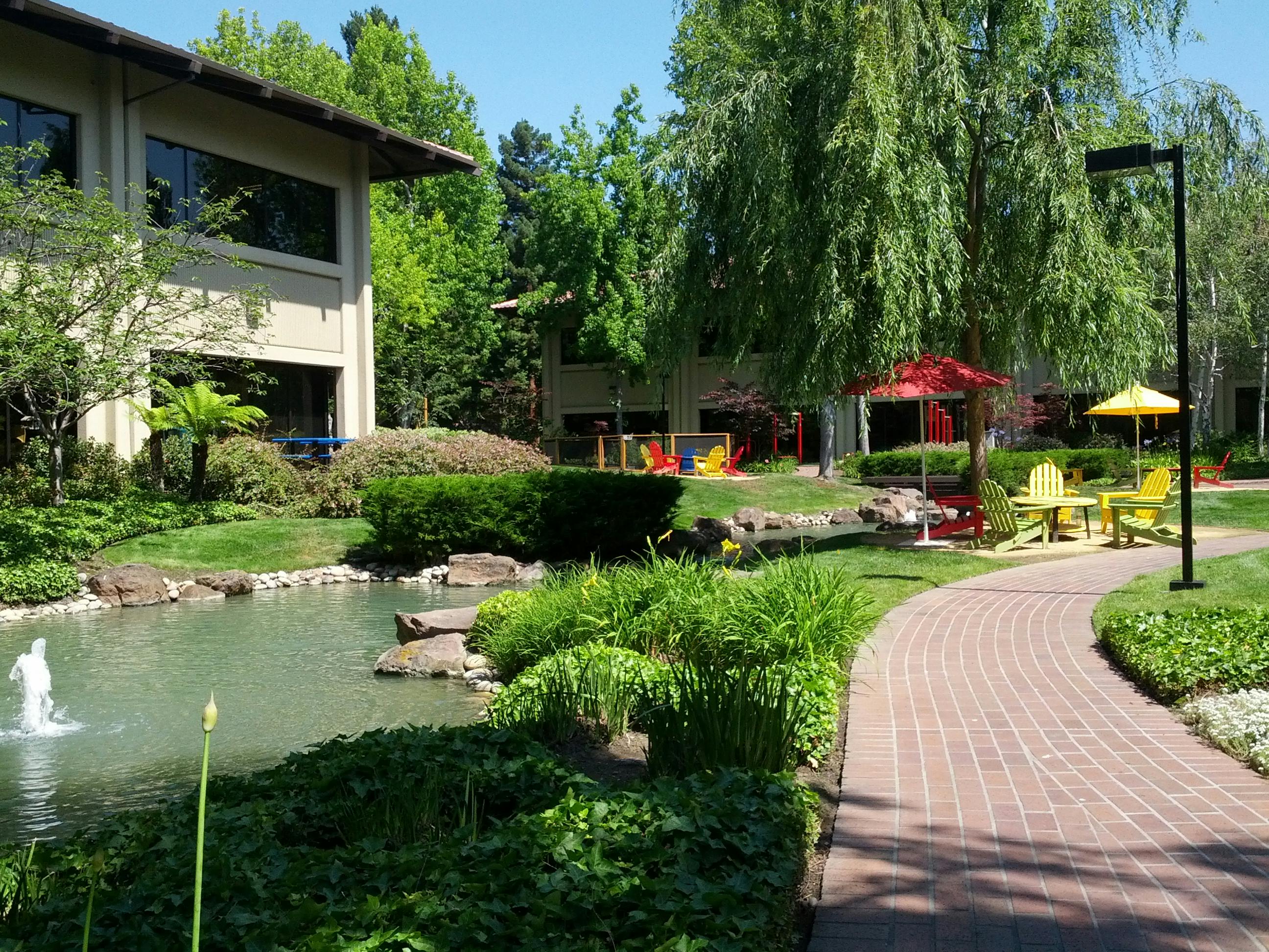 photograph of grounds at Google headquarters, with lawn chairs, picnic tables, and a pond