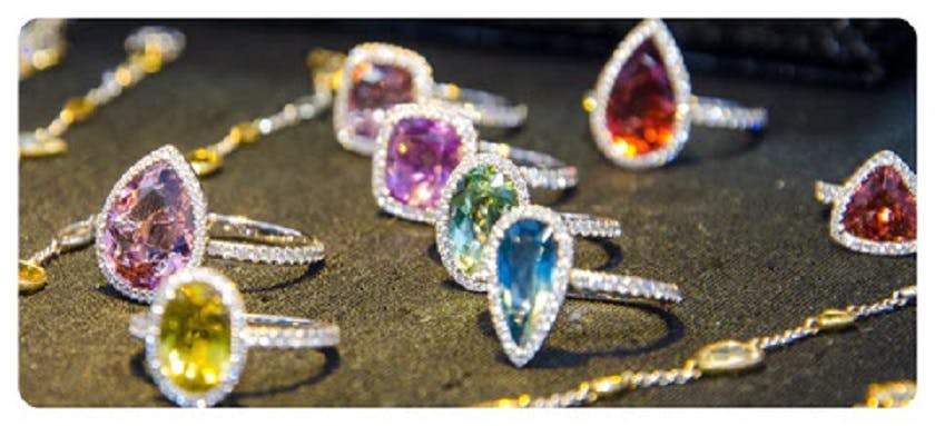 A photo of colorful gemstone rings and silver necklaces displayed on a table.