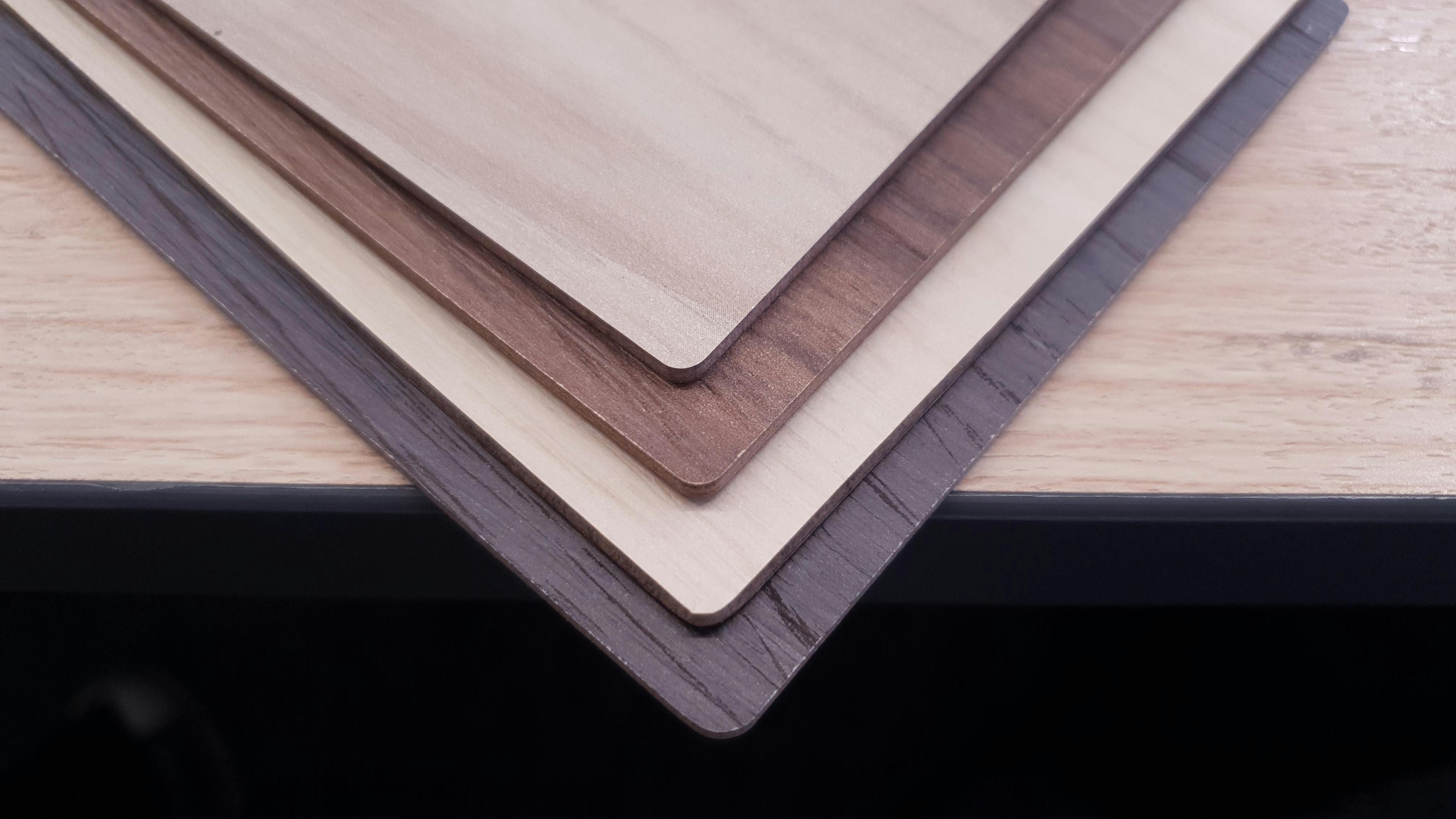 Papan melamine-faced MDF (MFM) dalam empat warna berbeda ditumpuk di atas sebuah meja kayu