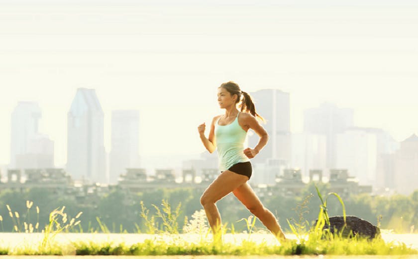 A woman running in a park with a city skyline in the background