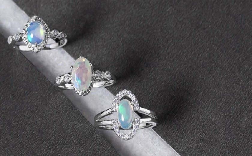 Close-up of three opal rings on a black table Whether the rings are silver or gold.