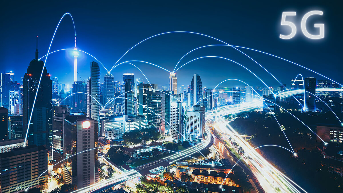 A night-time cityscape with illuminated buildings and roads. Blue lines represent connectivity between different points in the city, illustrating the concept of 5G technology, with "5G" text in the top right corner.