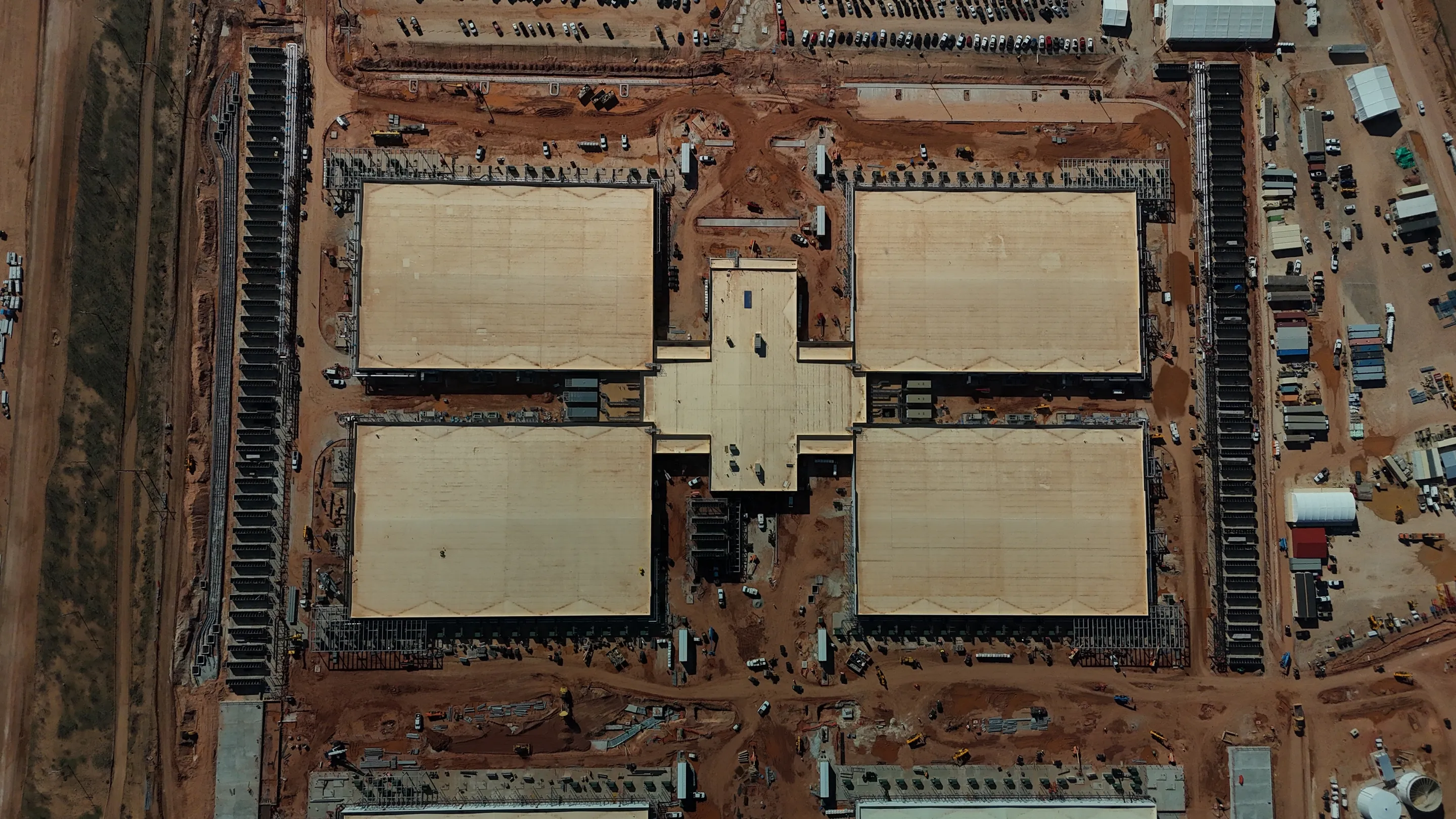 Closer overhead photograph of data-center buildings and surrounding equipment during construction at the Crusoe Abilene campus, published by DPR Construction.