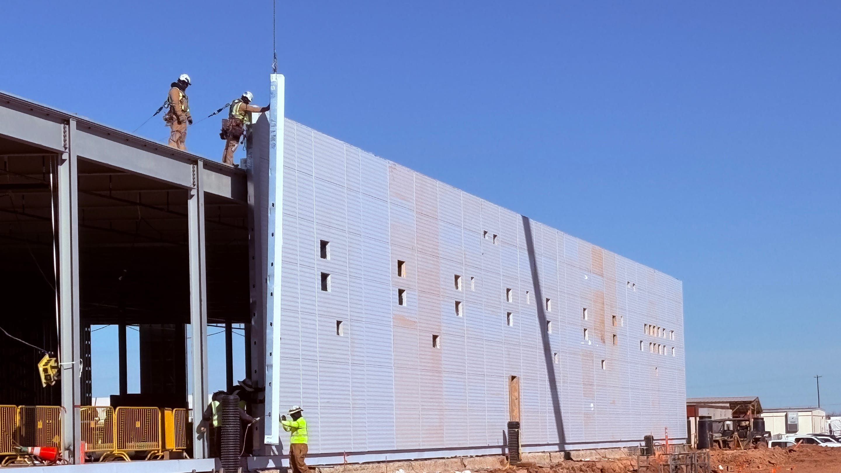 Construction workers installing exterior panels on a data-center building, in a close-up published by DPR Construction as part of its Abilene project gallery.